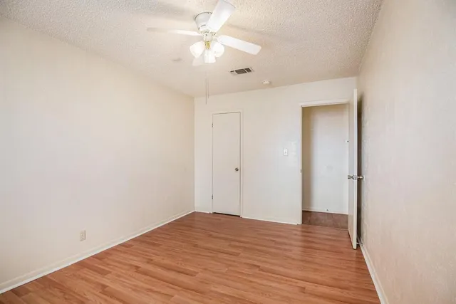 an empty room with wooden floor and ceiling fan