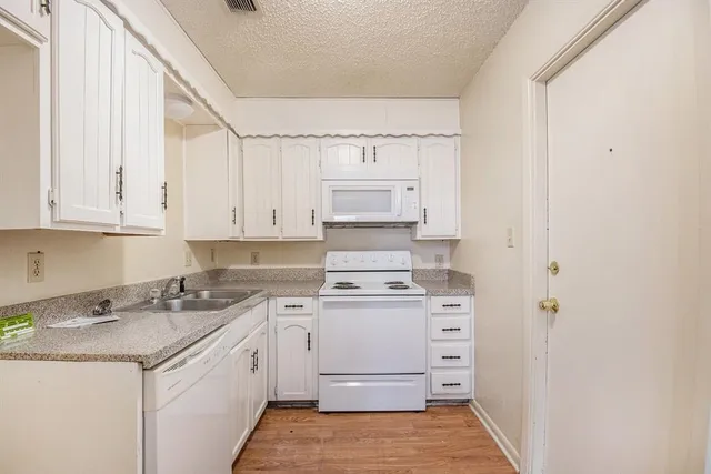 a kitchen with granite countertop white cabinets and white appliances