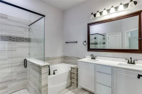 a bathroom with a bathtub shower sink vanity and mirror