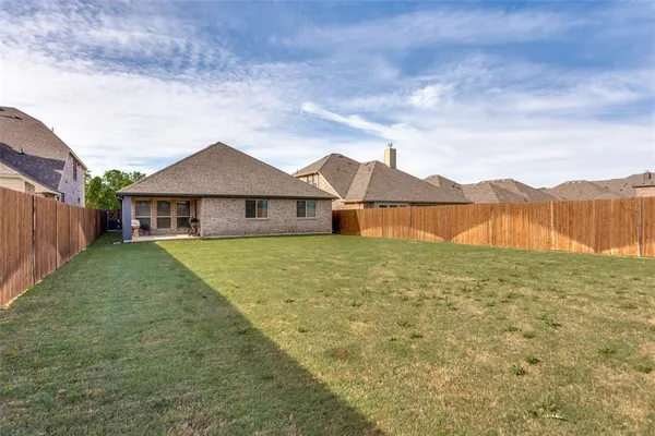 a view of a house with a yard and a large tree