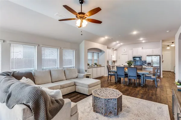 a living room with furniture kitchen view and a large window