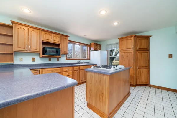 an empty room with wooden floor chandelier fan and windows