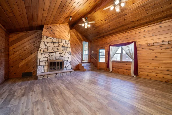 a view of an empty room with wooden floor a fireplace and windows