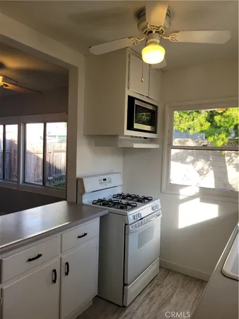 a kitchen with stainless steel appliances white cabinets a stove a sink and a window