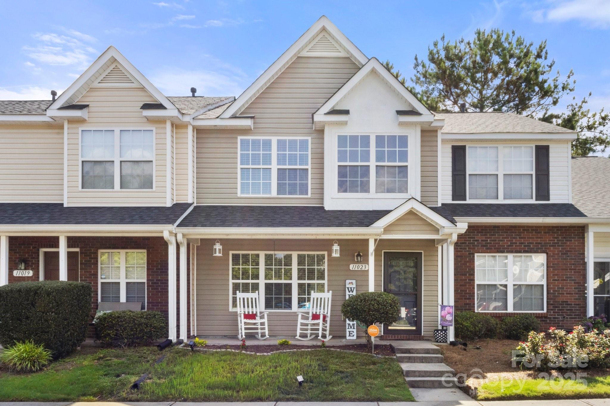 a front view of a house with a yard and potted plants