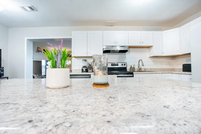a kitchen with stainless steel appliances a white stove top oven a white counter space and cabinets