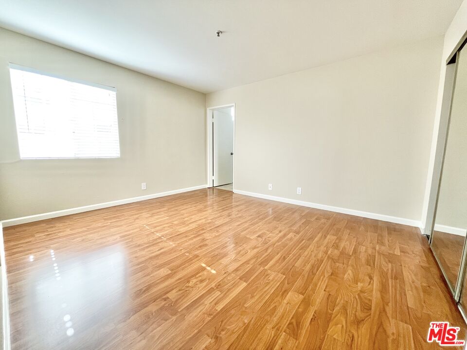 8722 Burton Way, Unit 102 Los Angeles, CA 90048 - Photo 4 of 11 a view of an empty room with wooden floor and a window