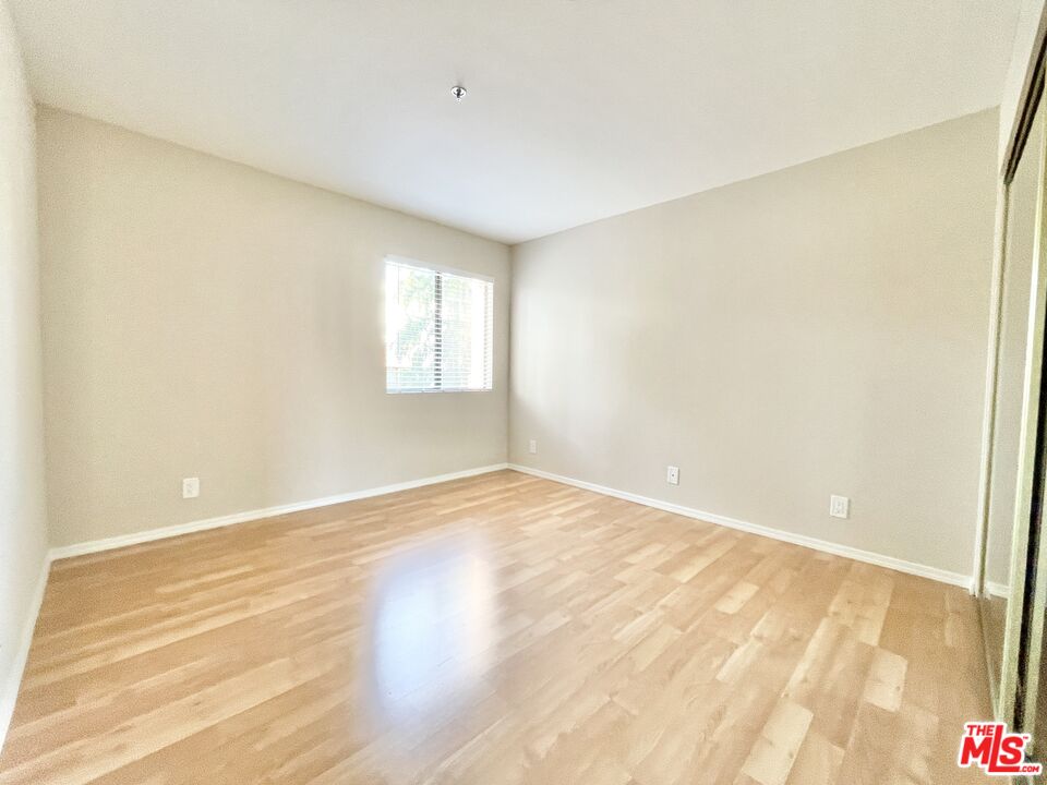 8722 Burton Way, Unit 102 Los Angeles, CA 90048 - Photo 6 of 11 a view of an empty room with wooden floor and a window