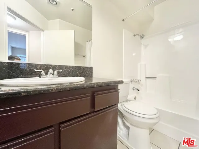 a bathroom with a granite countertop sink toilet and shower