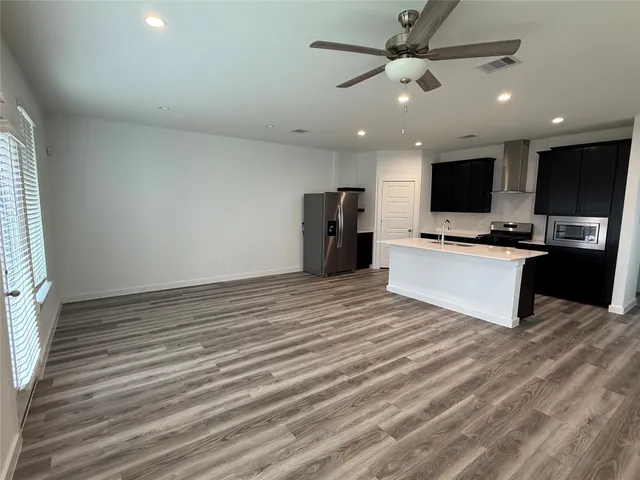a large white kitchen with wooden floor and a refrigerator