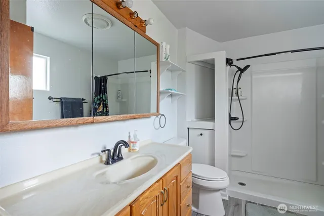 a bathroom with a granite countertop sink a toilet and shower