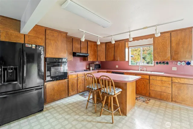 a kitchen with stainless steel appliances granite countertop a table chairs sink refrigerator and microwave