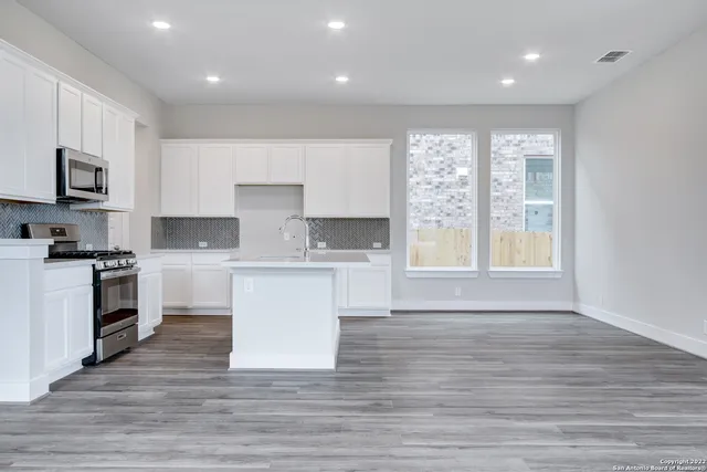 a large kitchen with stainless steel appliances granite countertop a stove a sink and a microwave