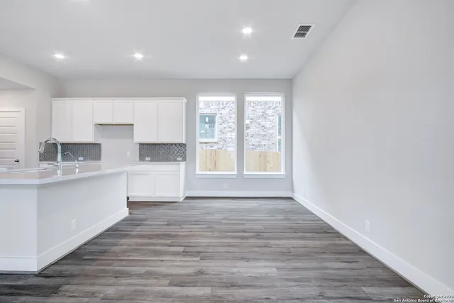 a large white kitchen with wooden floors and white walls