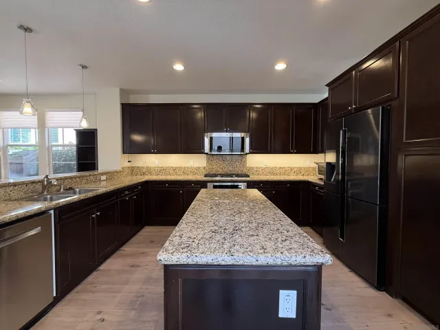 a kitchen with stainless steel appliances granite countertop a sink stove and refrigerator