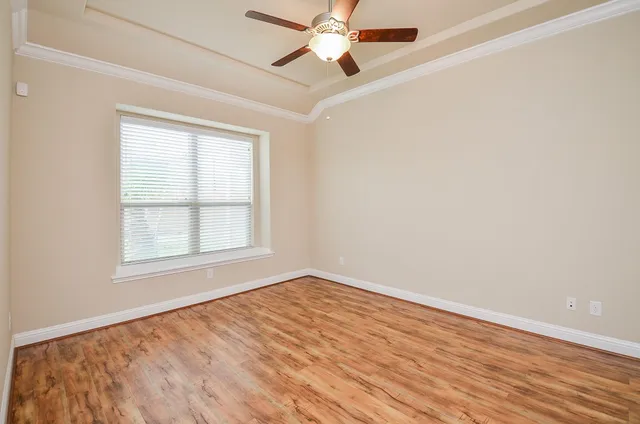 an empty room with wooden floor fan and windows