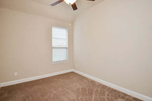 an empty room with a window and ceiling fan
