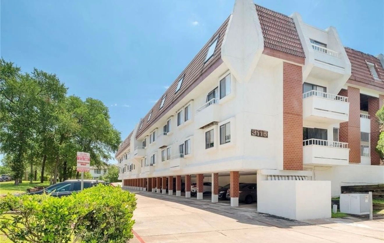 3115 Helms Street, Unit 111 Austin, TX 78705 - Photo 11 of 13 Multi-level residential building with balconies and ground-level covered parking offers convenient living.