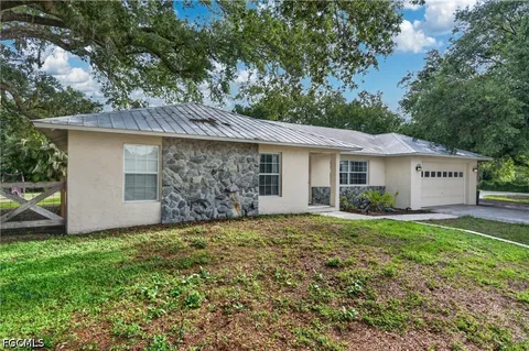 a view of a house with a yard and large tree