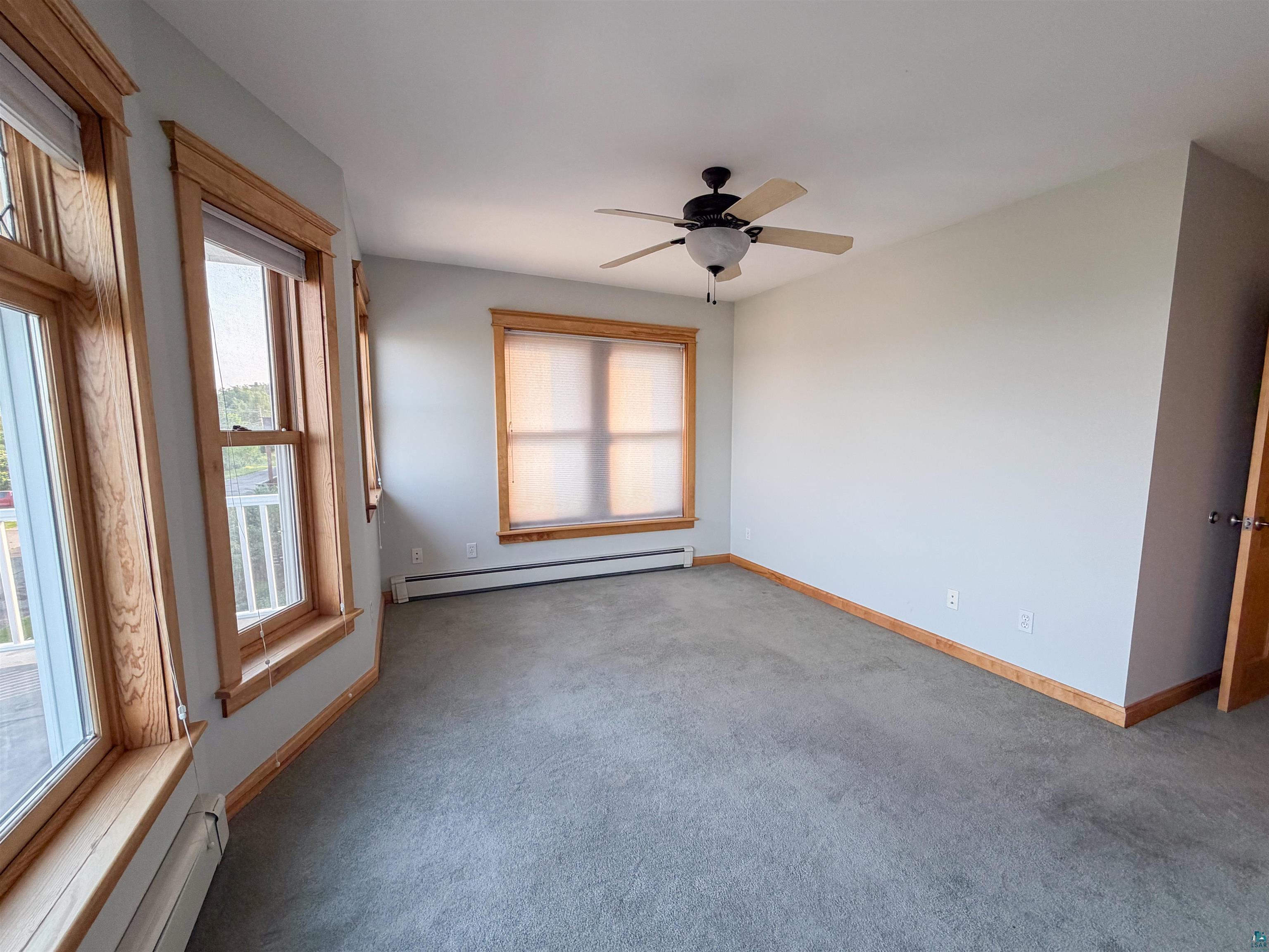 13 West 8th Street Duluth, MN 55806 - Photo 24 of 57 Carpeted room featuring multiple windows with wood trim, a ceiling fan, and baseboard heating