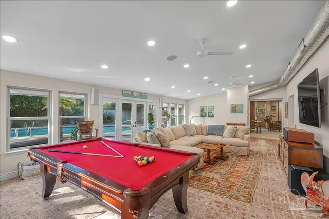 a living room with furniture pool table and glass windows