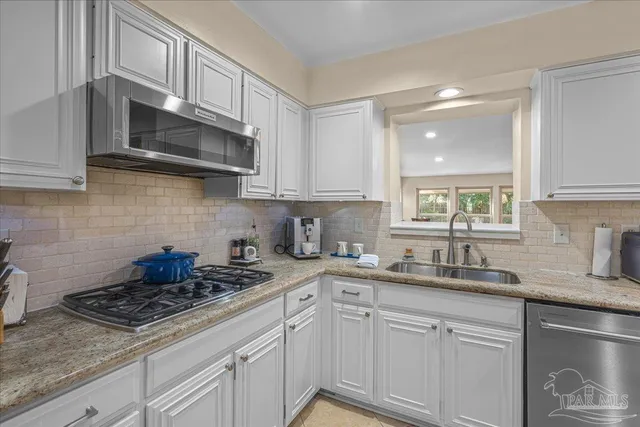 a kitchen with stainless steel appliances granite countertop white cabinets a stove a sink and dishwasher