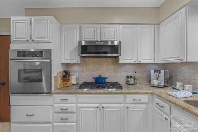a kitchen with granite countertop white cabinets and stainless steel appliances