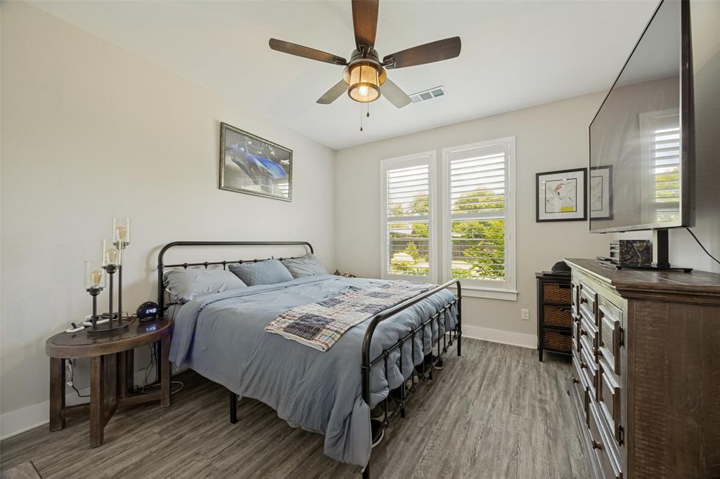 1105 Ranch Drive Bonham, TX 75418 - Photo 18 of 25 Room featuring wood-finish flooring, two large windows with blinds, and a ceiling fan with integrated lighting