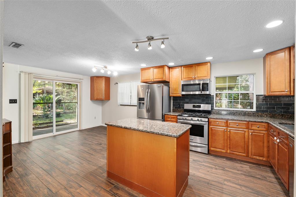630 Northwest 34th Street Gainesville, FL 32607 - Photo 14 of 84 a kitchen with stainless steel appliances granite countertop hardwood floor sink stove and wooden cabinets