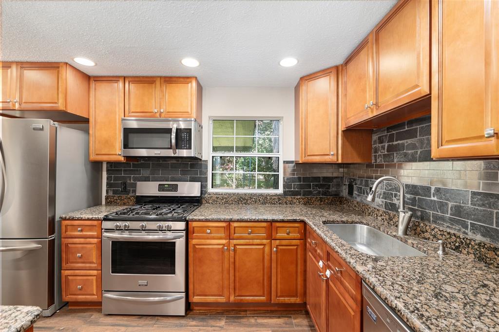 630 Northwest 34th Street Gainesville, FL 32607 - Photo 15 of 84 a kitchen with granite countertop a sink stainless steel appliances and cabinets