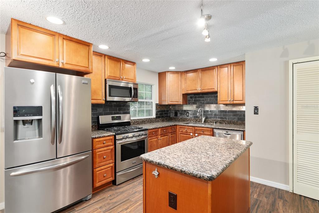 630 Northwest 34th Street Gainesville, FL 32607 - Photo 4 of 84 a kitchen with stainless steel appliances granite countertop a refrigerator a stove top oven a sink and dishwasher