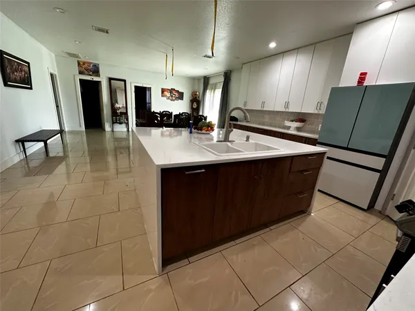 a kitchen with stainless steel appliances a sink a counter top space cabinets and a view of living room