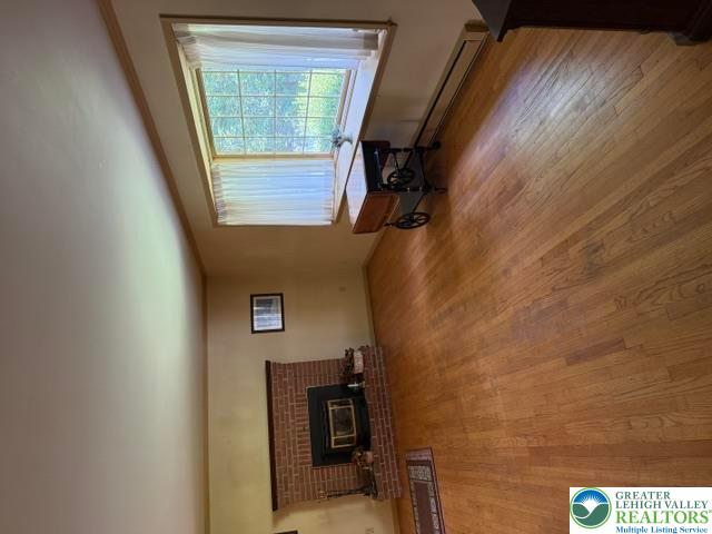 2045 Church Road Bethlehem, PA 18015 - Photo 16 of 42 A warm living space features rich hardwood floors and a cozy brick fireplace, illuminated by a large skylight.