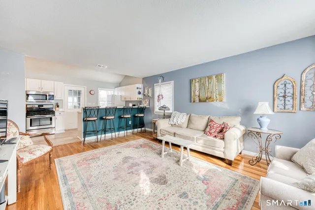 a living room with furniture and a large mirror next to a window