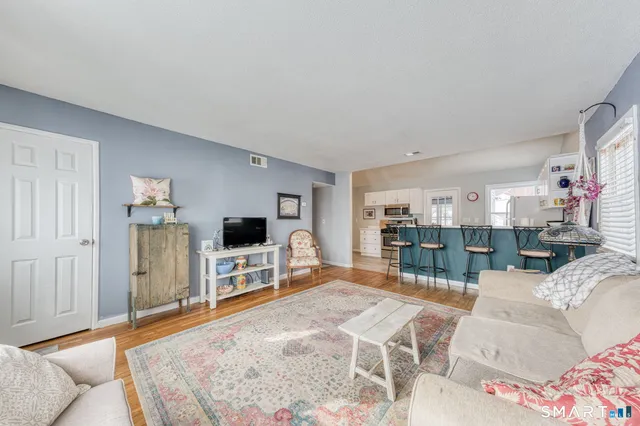 a kitchen with stainless steel appliances kitchen island granite countertop a dining table chairs and a refrigerator