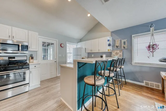 a kitchen with cabinets wooden floor and stainless steel appliances