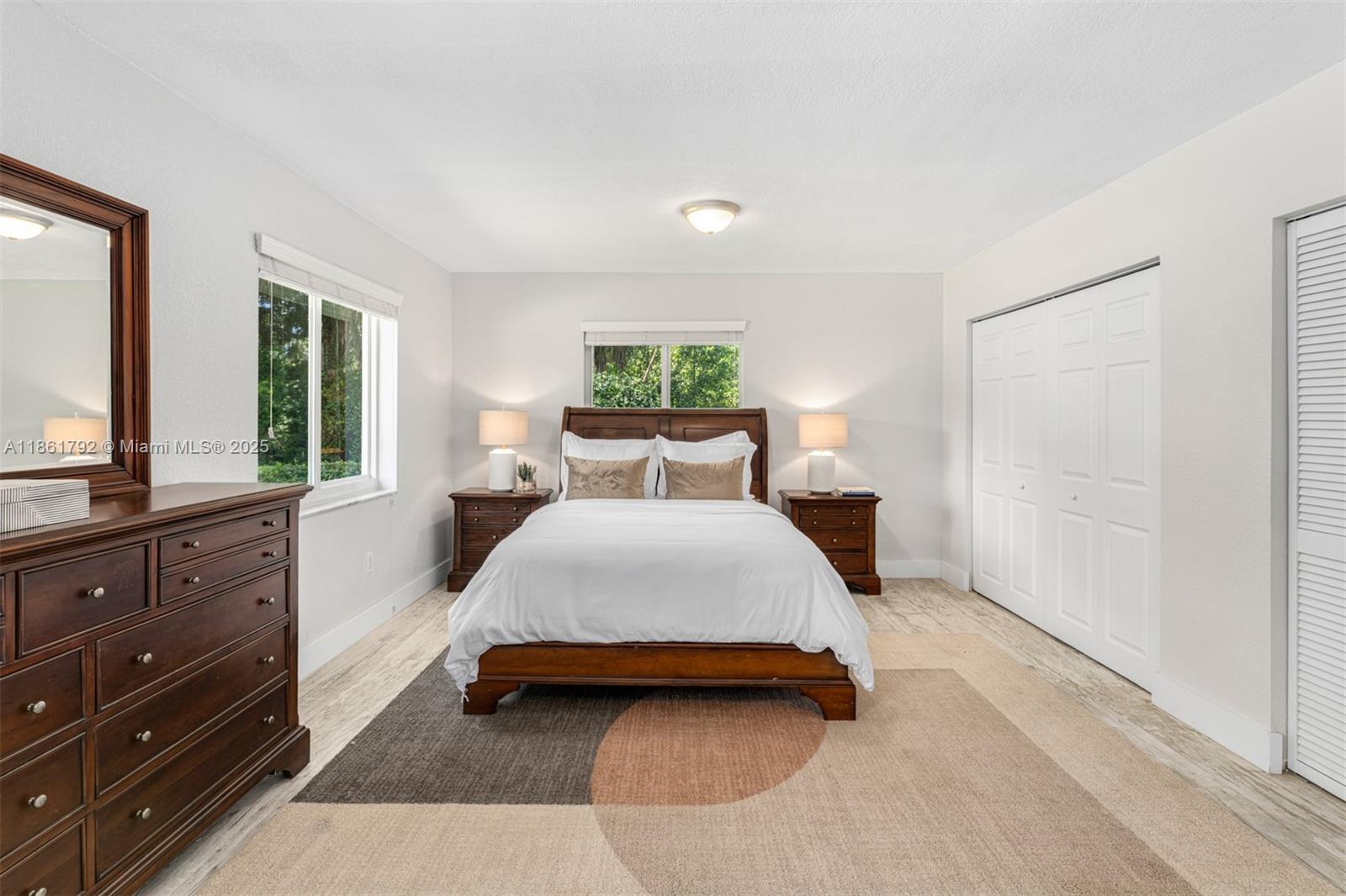 5940 Southwest 120th Street Pinecrest, FL 33156 - Photo 18 of 40 a bedroom with a large bed and a dresser with mirror