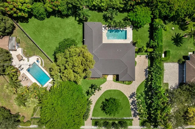 an aerial view of residential house with outdoor space and trees all around