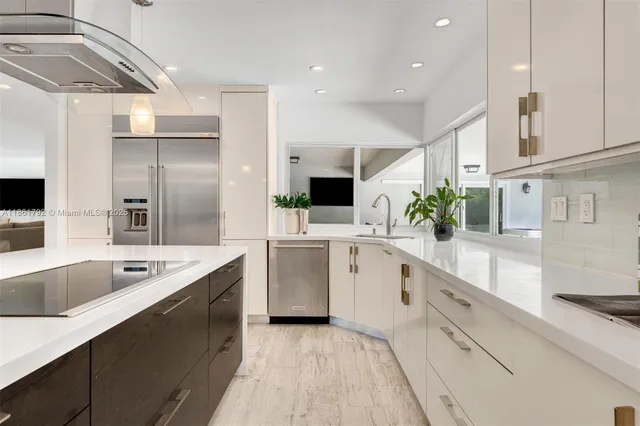 a large white kitchen with a sink and stainless steel appliances