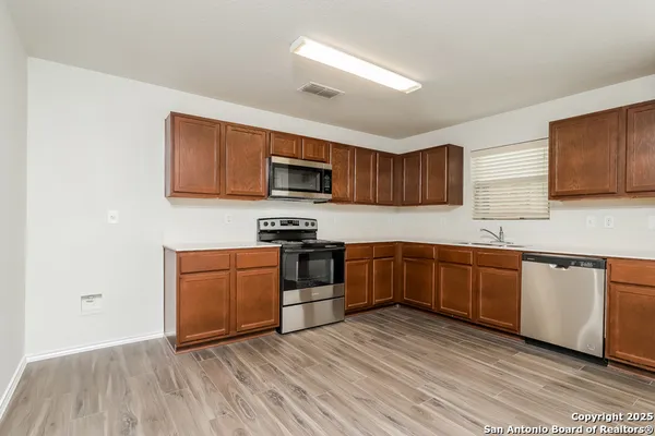 a kitchen with stainless steel appliances granite countertop a stove top oven a sink dishwasher and a microwave oven on the wooden floor