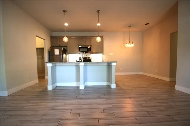 a view of kitchen with kitchen island microwave and wooden floor