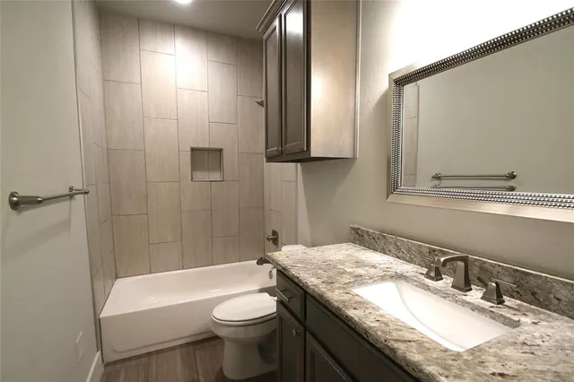 a bathroom with a granite countertop sink a toilet and shower