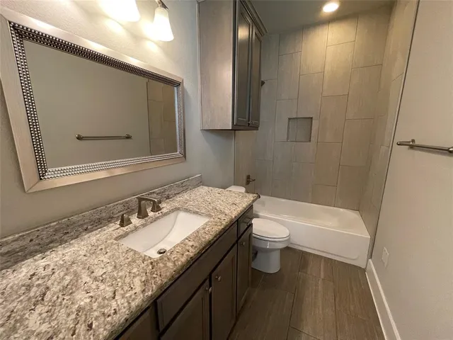 a bathroom with a granite countertop sink a toilet and a bathtub