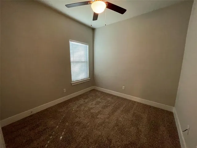 an empty room with a chandelier fan and windows