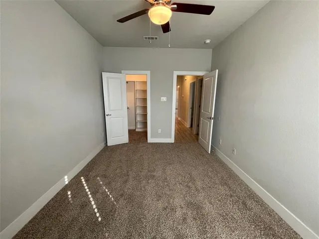 an empty room with closet and a chandelier fan