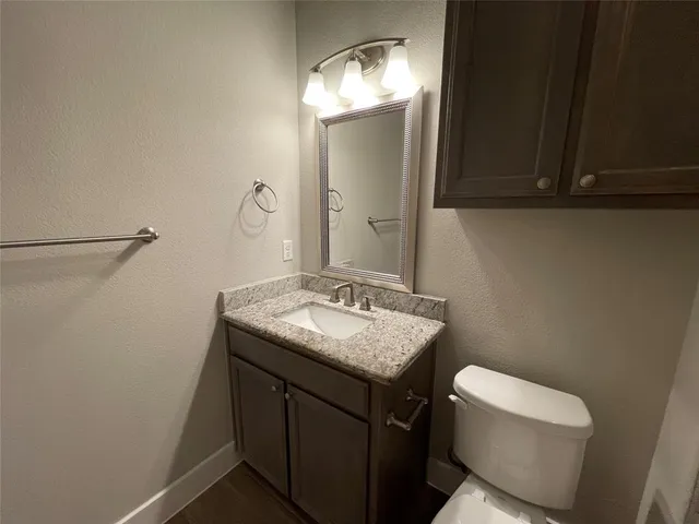 a bathroom with a granite countertop sink a toilet and a mirror