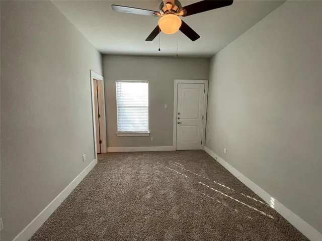 an empty room with a window and a ceiling fan