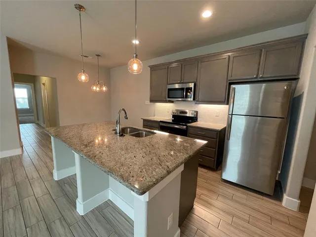 a kitchen with stainless steel appliances granite countertop a sink a refrigerator and a stove