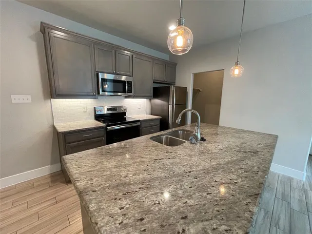 a kitchen with granite countertop a stove refrigerator and microwave