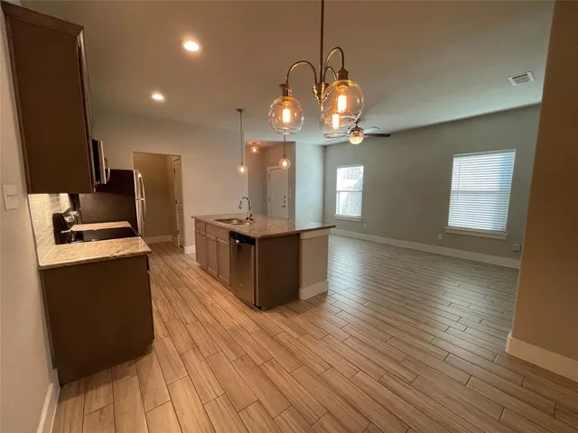 a view of a kitchen with granite countertop wooden floor and stainless steel appliances